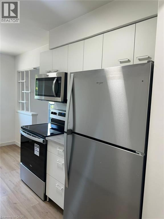 Kitchen with stainless steel appliances, white cabinetry, light wood-type flooring, and modern cabinets - 145 Macgregor Crescent Unit# 1, Waterloo, ON - Indoor Photo Showing Kitchen