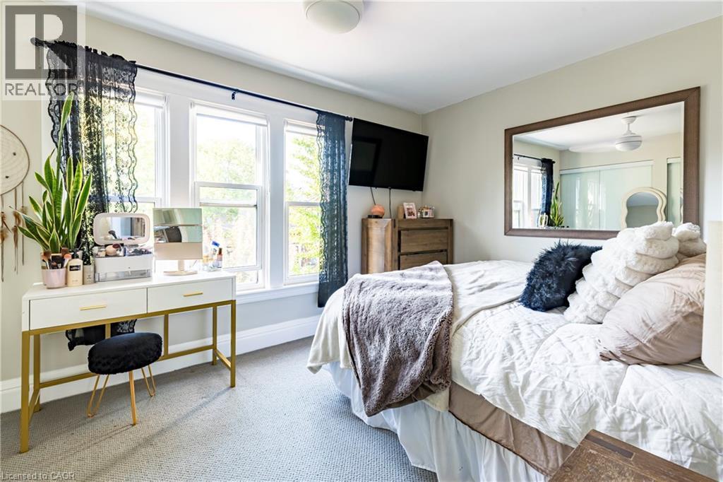 Bedroom with multiple windows, carpet flooring, and an office area - 58 Chatham Street, Hamilton, ON - Indoor Photo Showing Bedroom