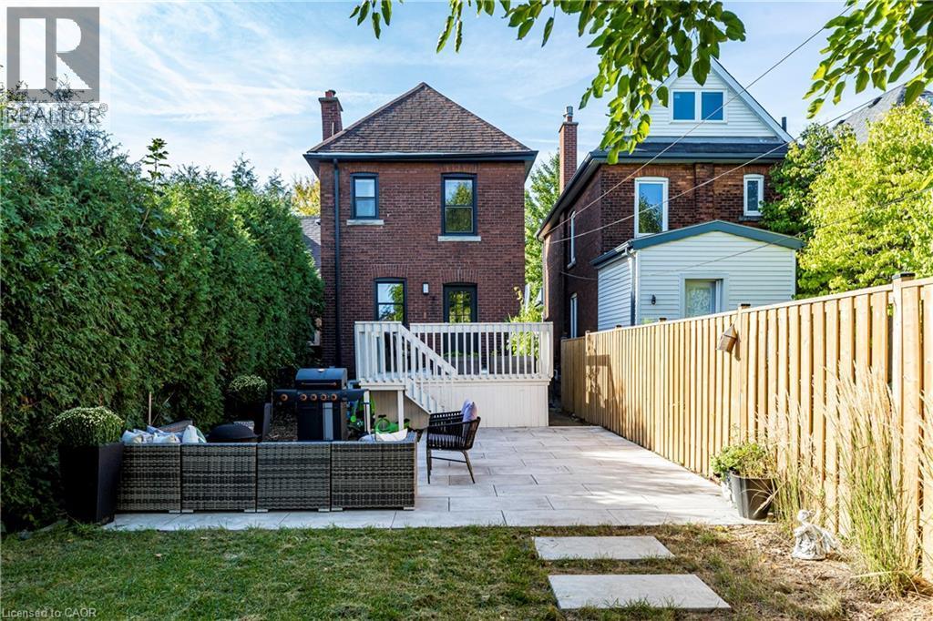 Back of property featuring a patio, an outdoor hangout area, brick siding, and a chimney - 58 Chatham Street, Hamilton, ON - Outdoor With Deck Patio Veranda