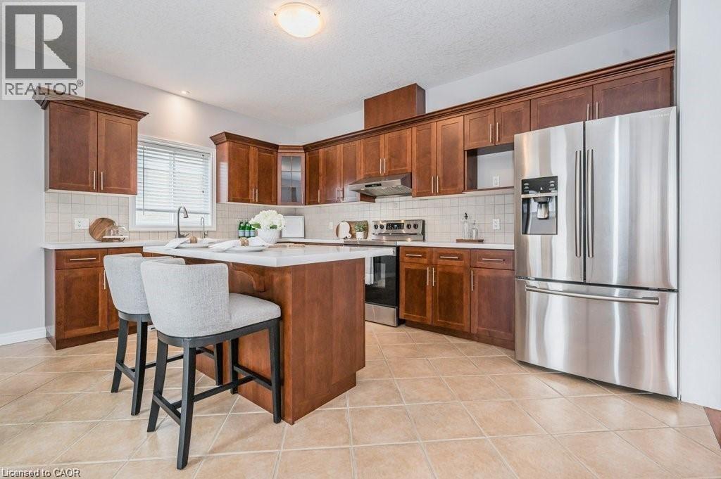 Kitchen with stainless steel appliances, a breakfast bar, light tile patterned floors, tasteful backsplash, and a textured ceiling - 609 Woolgrass Avenue, Waterloo, ON - Indoor Photo Showing Kitchen