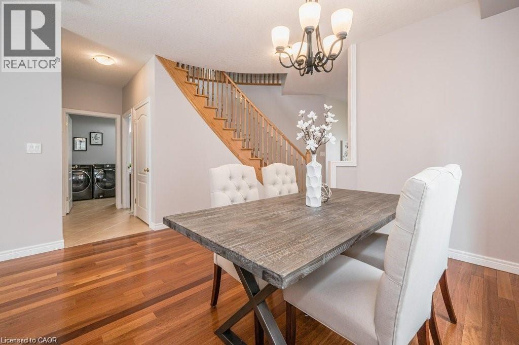 Dining area with a chandelier, washing machine and clothes dryer, light wood-style floors, and stairway - 609 Woolgrass Avenue, Waterloo, ON - Indoor Photo Showing Dining Room
