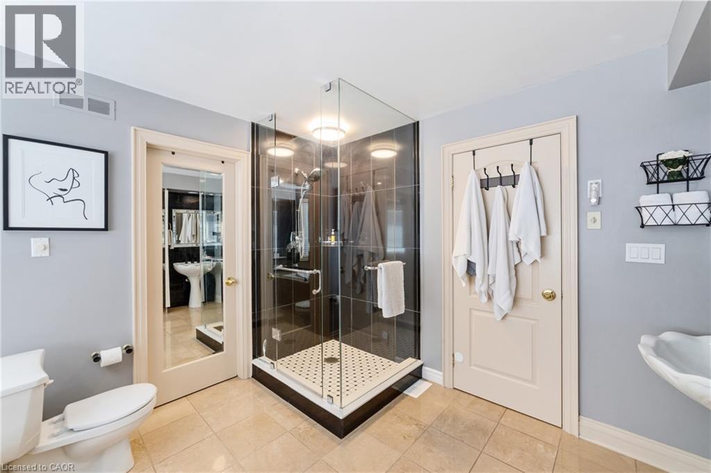 Ensuite with walk-in closet beside the shower with mirrored framed door, newly installed upgraded shower stall with glass enclosure, his & her pedestal sinks - 7775 St. Augustine Crescent, Niagara Falls, ON - Indoor Photo Showing Bathroom