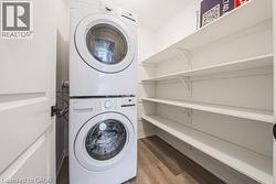 Laundry area with light wood-style flooring and stacked washing machine and dryer -