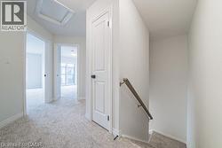 Corridor with an upstairs landing, light carpet, and attic access -
