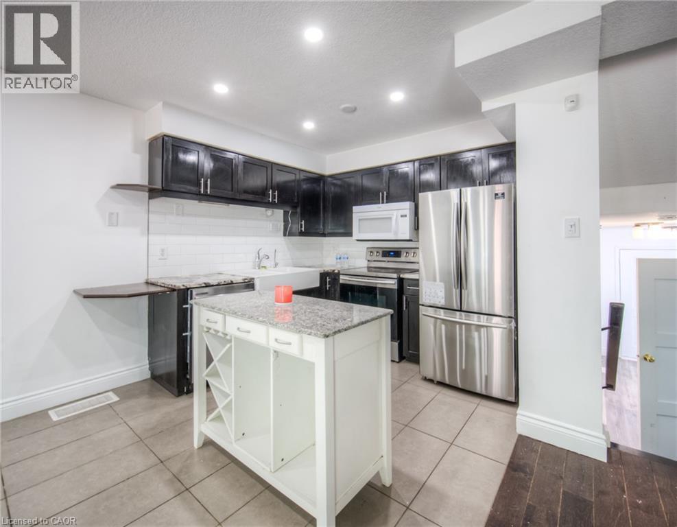 Kitchen with appliances with stainless steel finishes, light stone counters, tasteful backsplash, open shelves, and a center island - 20 Bankside Drive, Kitchener, ON - Indoor Photo Showing Kitchen