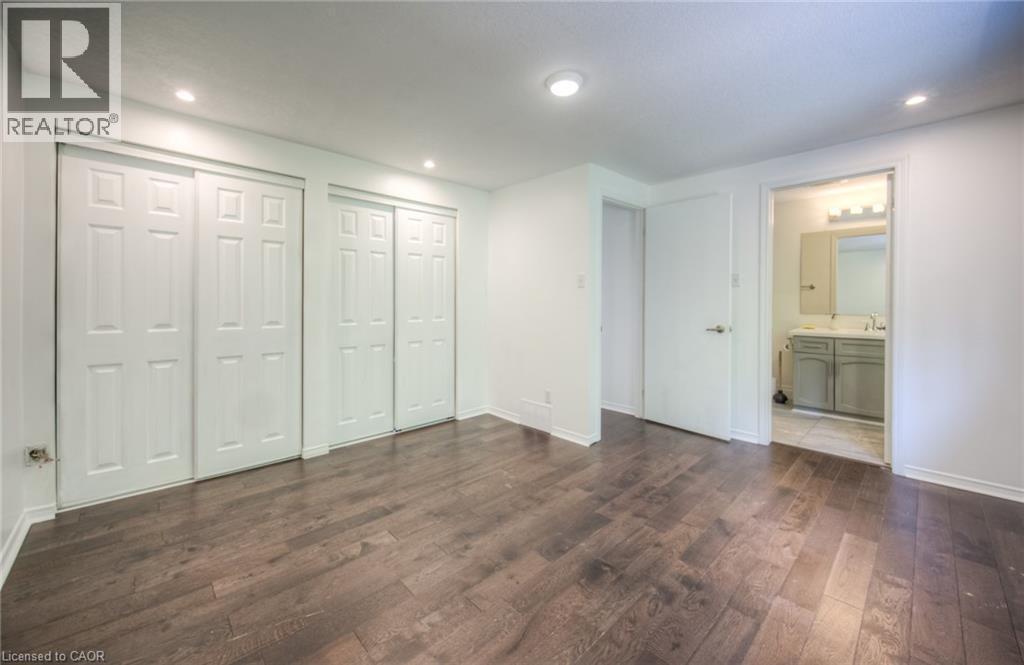 Unfurnished bedroom with two closets, dark wood-style floors, recessed lighting, and ensuite bathroom - 20 Bankside Drive, Kitchener, ON - Indoor Photo Showing Other Room