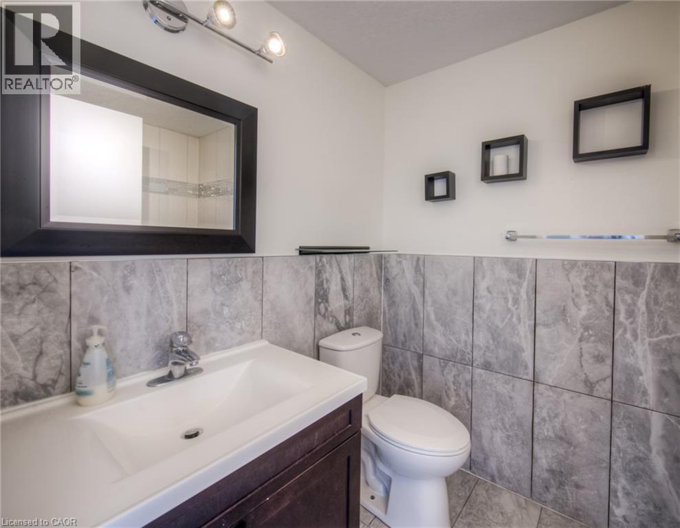 Full bath with vanity, tile walls, a wainscoted wall, and light tile patterned floors - 20 Bankside Drive, Kitchener, ON - Indoor Photo Showing Bathroom