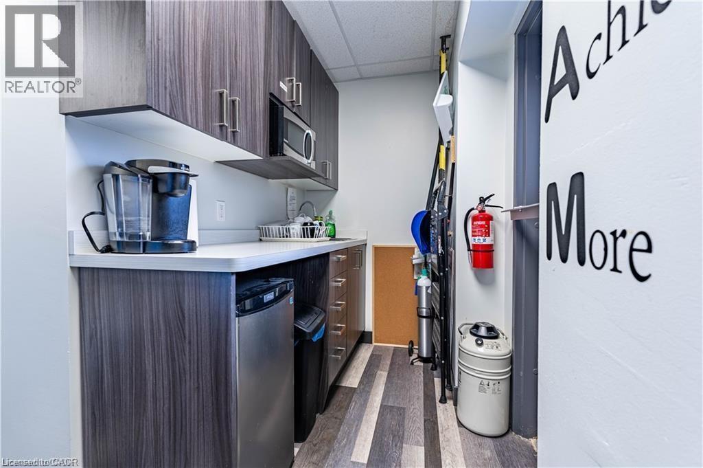 Kitchen with light countertops, a drop ceiling, modern cabinets, dark wood finished floors, and dark brown cabinets - 10 Main Street, Mississauga, ON