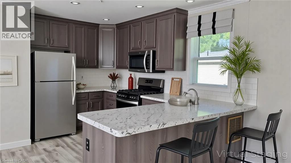 Kitchen with appliances with stainless steel finishes, a peninsula, backsplash, a breakfast bar, and ornamental molding - 24 Macpherson Crescent, Flamborough, ON - Indoor Photo Showing Kitchen With Upgraded Kitchen
