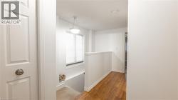 Hall with baseboards, an upstairs landing, and wood finished floors -