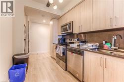 Kitchen with sink, light wood-type flooring, light brown cabinetry, tasteful backsplash, and stainless steel appliances -