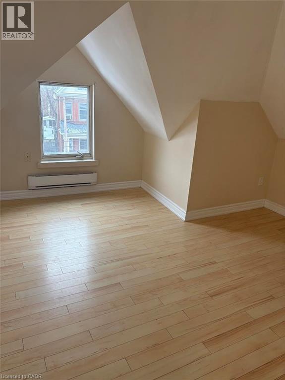 Bonus room featuring vaulted ceiling, light wood-type flooring, and baseboard heating - 95 Sanford Avenue N, Hamilton, ON - Indoor Photo Showing Other Room