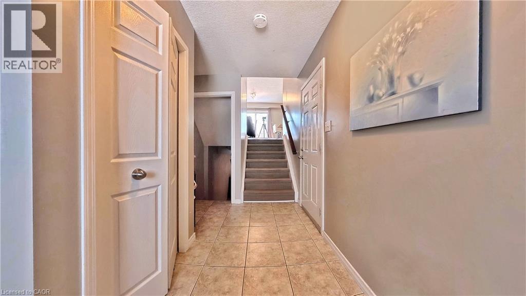 Hallway featuring a textured ceiling, stairway, and light tile patterned flooring - 206 Westmeadow Drive, Kitchener, ON - Indoor Photo Showing Other Room