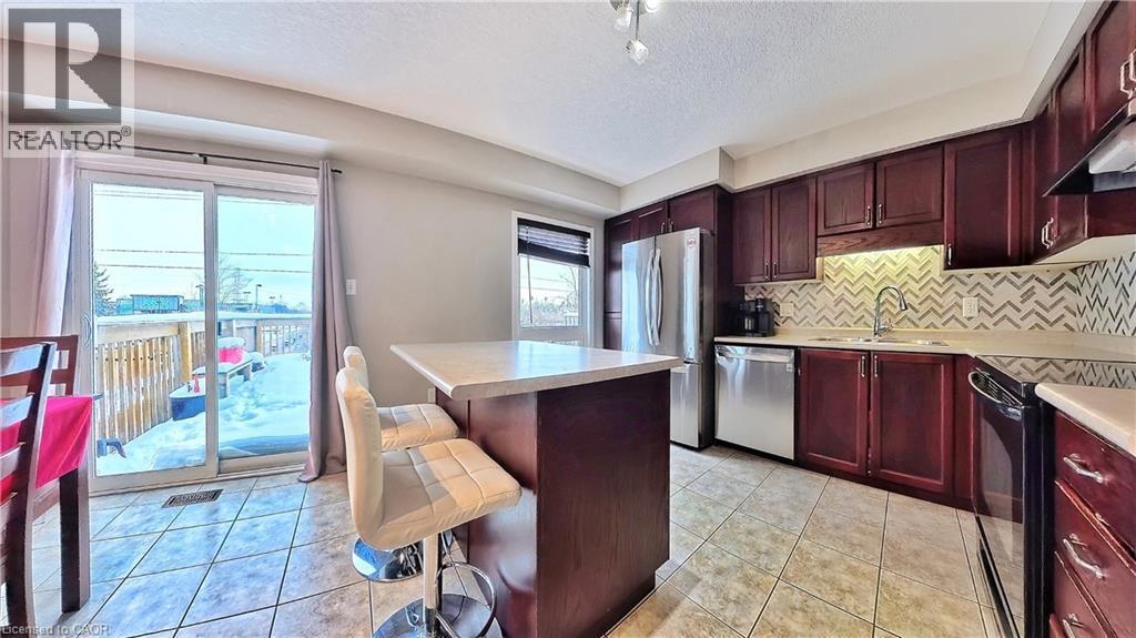 Kitchen with reddish brown cabinets, light tile patterned flooring, appliances with stainless steel finishes, a center island, and a textured ceiling - 206 Westmeadow Drive, Kitchener, ON - Indoor Photo Showing Kitchen With Stainless Steel Kitchen With Double Sink With Upgraded Kitchen