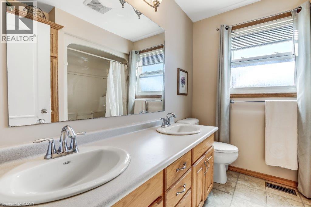 Full bath featuring healthy amount of natural light, double vanity, and curtained shower - 2 Falls Crescent, Simcoe, ON - Indoor Photo Showing Bathroom