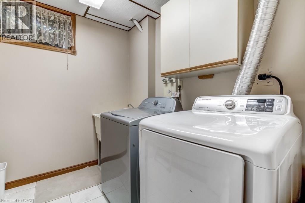 Laundry room with light tile patterned flooring, independent washer and dryer, and cabinet space - 2 Falls Crescent, Simcoe, ON - Indoor Photo Showing Laundry Room