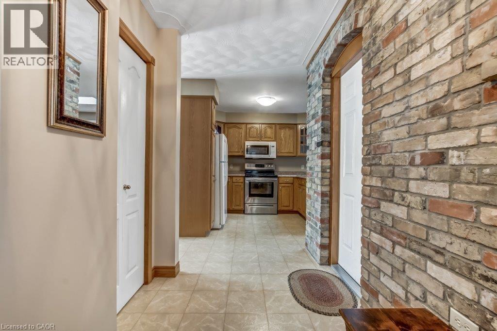 Hall with brick wall and light tile patterned floors - 2 Falls Crescent, Simcoe, ON - Indoor