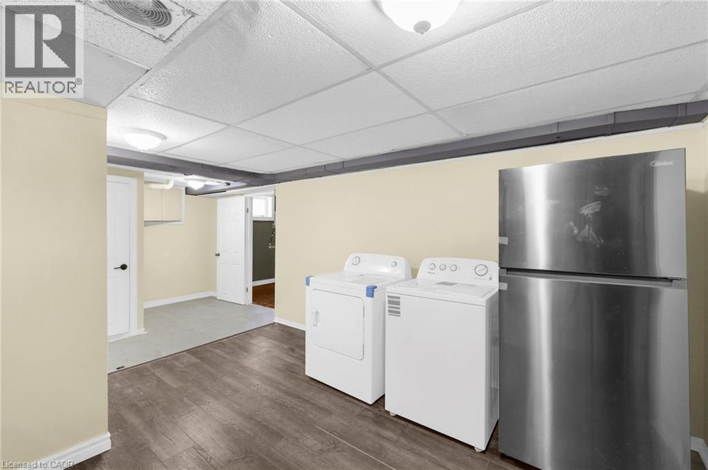Laundry room featuring dark wood finished floors, a drop ceiling, and washing machine and dryer - 368 Upper Kenilworth Avenue, Hamilton, ON - Indoor Photo Showing Laundry Room