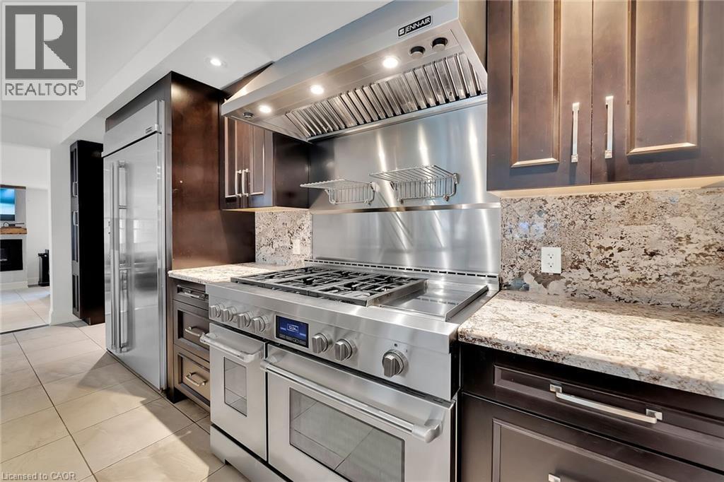 Kitchen featuring exhaust hood, light stone countertops, premium appliances, dark brown cabinetry, and recessed lighting - 404 Mountain Brow Boulevard E, Hamilton, ON - Indoor Photo Showing Kitchen With Upgraded Kitchen