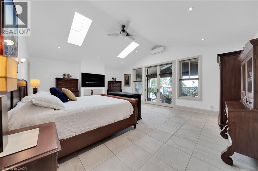 Bedroom featuring vaulted ceiling, access to exterior, a wall mounted air conditioner, light tile patterned flooring, and a skylight - 404 Mountain Brow Boulevard E, Hamilton, ON - Indoor Photo Showing Bedroom