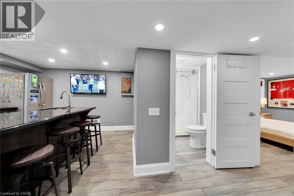 Indoor wet bar featuring recessed lighting, light wood-type flooring, dark countertops, and stainless steel fridge with ice dispenser - 404 Mountain Brow Boulevard E, Hamilton, ON - Indoor