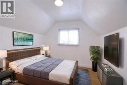 Bedroom staged with lofted ceiling and light colored carpet -