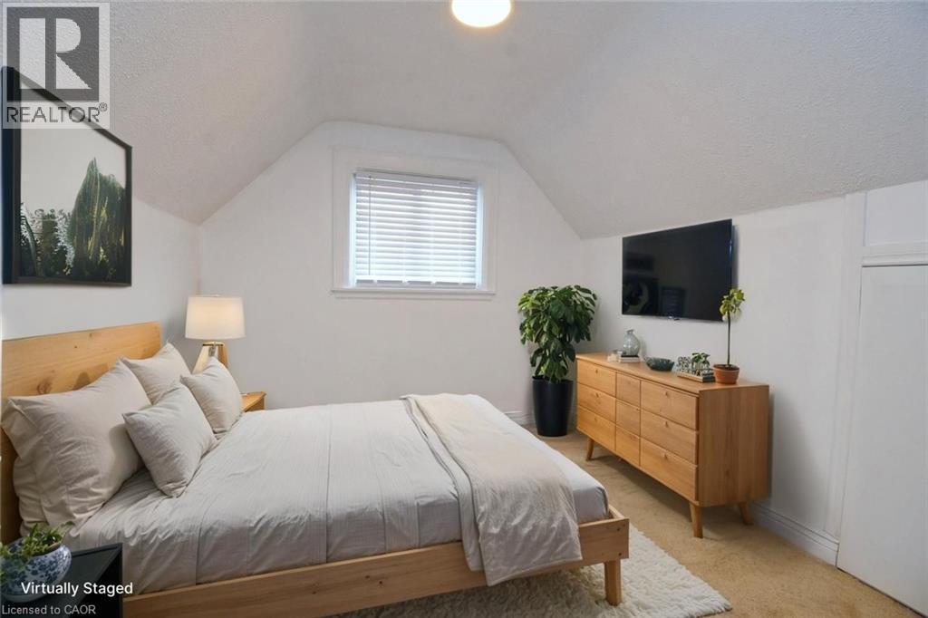 Bedroom staged featuring light colored carpet, vaulted ceiling, and a textured ceiling - 215 Walter Avenue S, Hamilton, ON - Indoor Photo Showing Bedroom