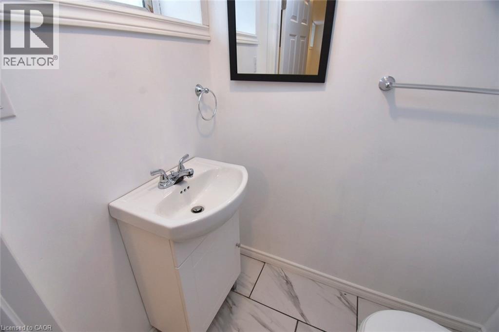 Bathroom featuring vanity and marble look tiles - 215 Walter Avenue S, Hamilton, ON - Indoor Photo Showing Bathroom