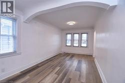 Unfurnished room featuring arched walkways and wood finished floors -