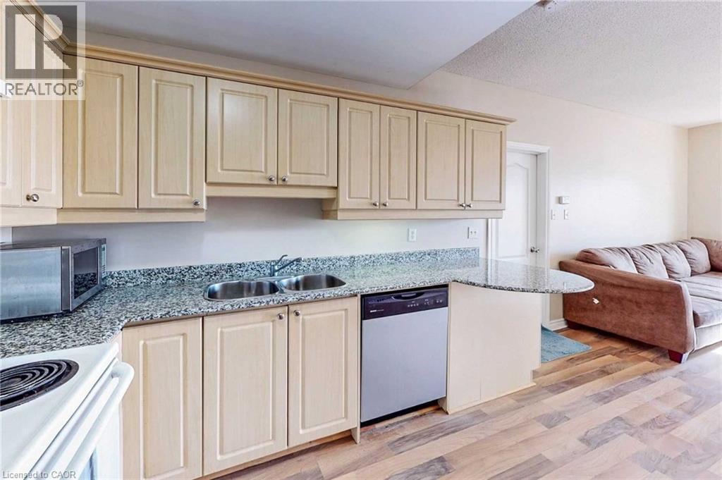 Kitchen with sink, light wood-type flooring, a textured ceiling, light stone counters, and stainless steel appliances - 135 James Street Unit# 608, Hamilton, ON - Indoor Photo Showing Kitchen With Double Sink