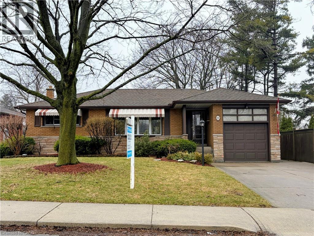 View of front of home with brick siding, driveway, an attached garage, and a shingled roof - 98 Laurier Avenue, Hamilton, ON