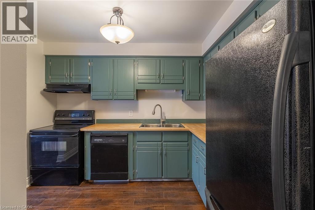 Kitchen featuring black appliances, light countertops, under cabinet range hood, dark wood finished floors, and green cabinetry - 58 Romy Crescent, Thorold, ON - Indoor Photo Showing Kitchen With Double Sink