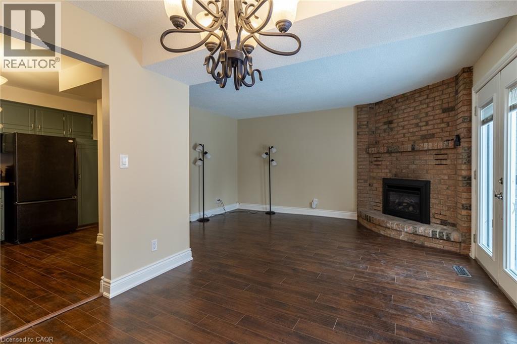 Unfurnished living room with dark wood-style floors, a fireplace, a chandelier, and a textured ceiling - 58 Romy Crescent, Thorold, ON - Indoor With Fireplace