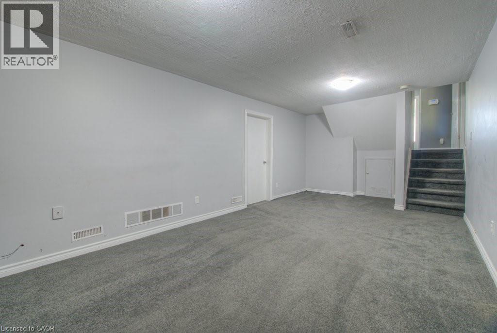 Finished basement with a textured ceiling, stairs, and carpet floors - 46 Guerin Avenue, Kitchener, ON - Indoor Photo Showing Other Room