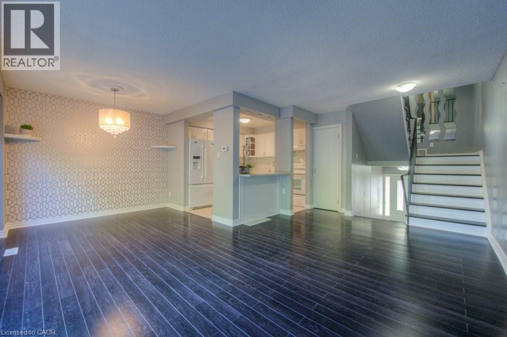 Unfurnished living room featuring wallpapered walls, stairs, dark wood-type flooring, and a textured ceiling - 46 Guerin Avenue, Kitchener, ON - Indoor Photo Showing Other Room