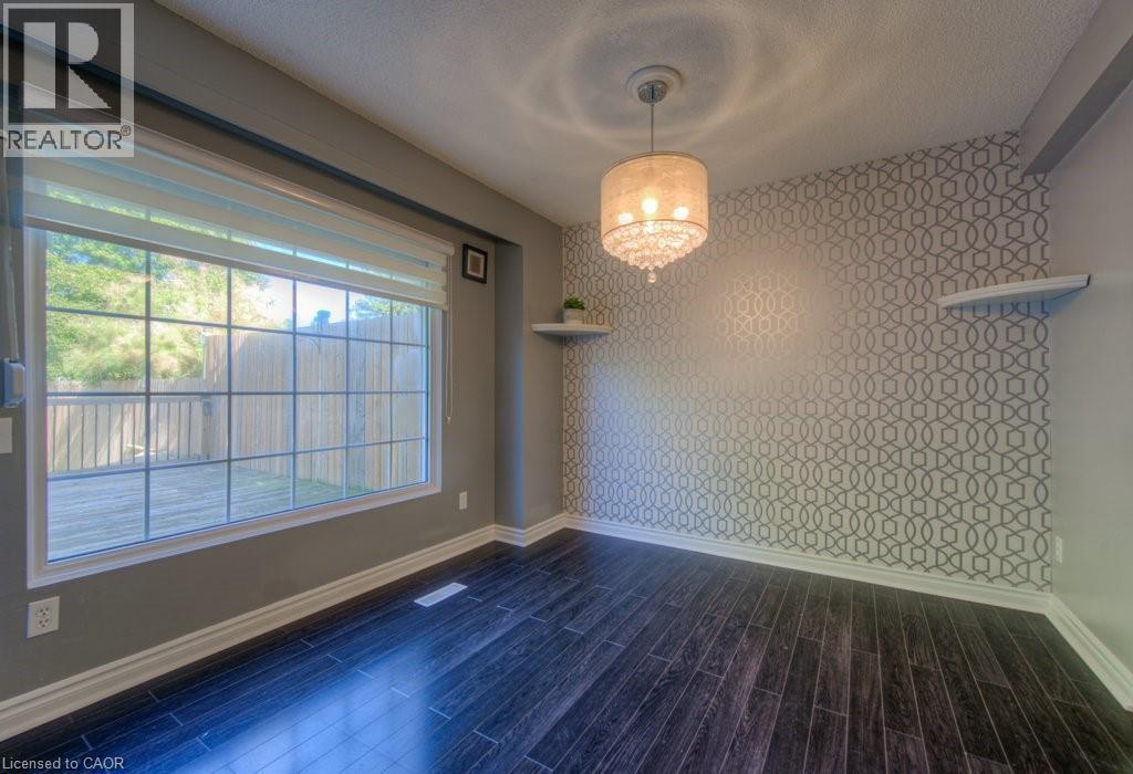 Unfurnished dining area featuring wallpapered walls, a chandelier, dark wood-type flooring, and an accent wall - 46 Guerin Avenue, Kitchener, ON - Indoor Photo Showing Other Room