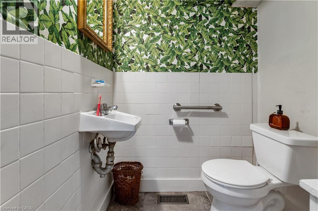 Bathroom featuring wallpapered walls, wainscoting, and tile walls - 193 Locke Street N, Hamilton, ON - Indoor Photo Showing Bathroom