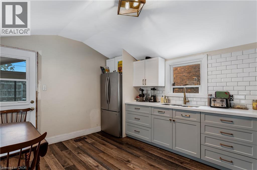 Kitchen featuring freestanding refrigerator, dark wood-type flooring, decorative backsplash, vaulted ceiling, and white cabinets - 193 Locke Street N, Hamilton, ON - Indoor Photo Showing Other Room