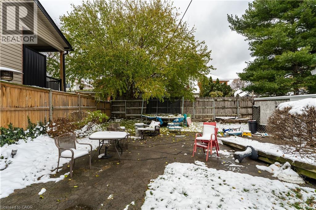 Snow covered patio with a patio and a fenced backyard - 193 Locke Street N, Hamilton, ON - Outdoor With Backyard