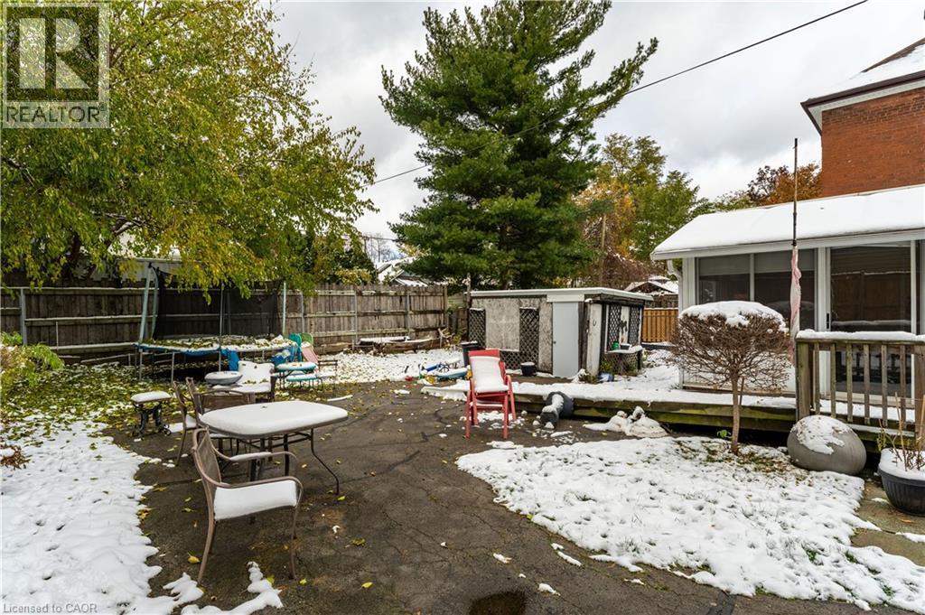 Snow covered patio featuring a trampoline, a patio area, a fenced backyard, a deck, and a storage unit - 193 Locke Street N, Hamilton, ON - Outdoor