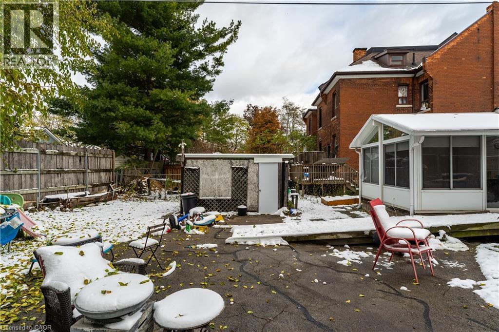 Snow covered patio featuring a shed, a sunroom, a patio area, and a fenced backyard - 193 Locke Street N, Hamilton, ON - Outdoor