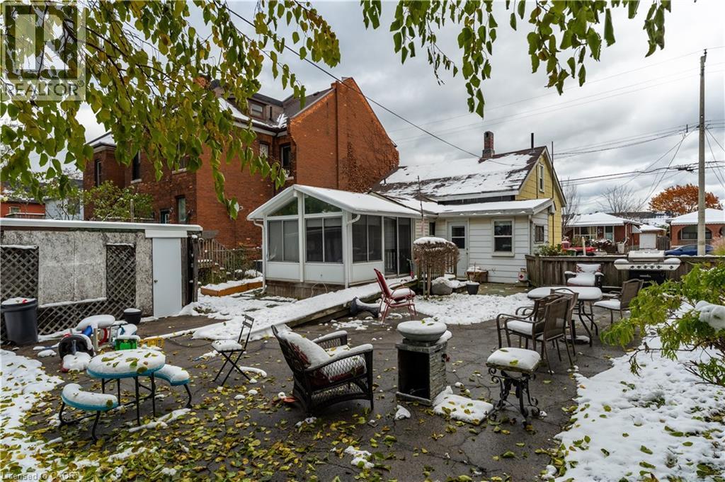 Snow covered back of property featuring a patio area and a sunroom - 193 Locke Street N, Hamilton, ON - Outdoor