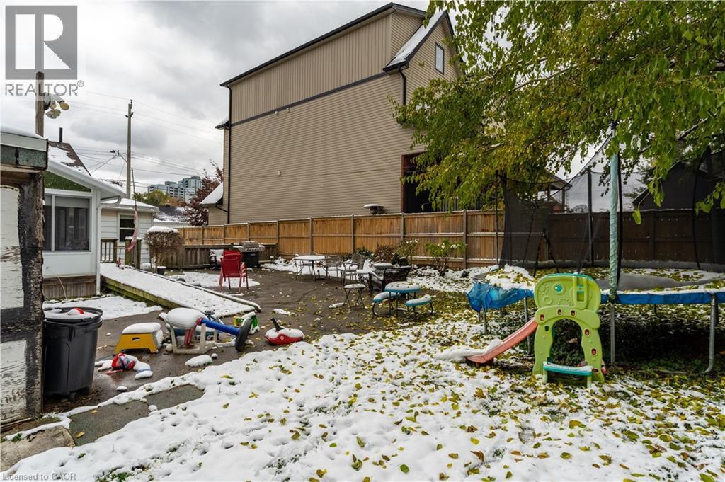 Snowy yard with a patio area, a trampoline, a fenced backyard, and a sunroom - 193 Locke Street N, Hamilton, ON - Outdoor