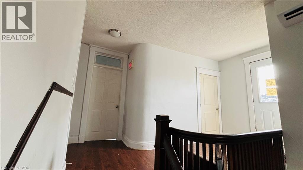 Hall featuring a textured ceiling, dark wood-style floors, an upstairs landing, and a wall unit AC - 30 Regina Street N, Waterloo, ON - Indoor Photo Showing Other Room