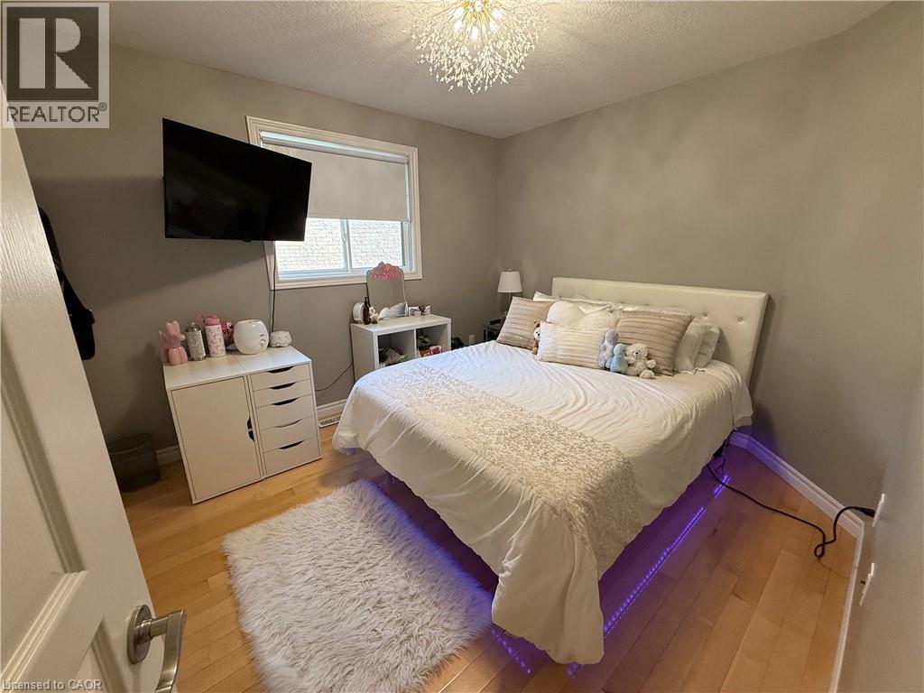 Bedroom featuring a textured ceiling, light wood-style flooring, and a chandelier - 11 Donatello Court, Hamilton, ON - Indoor Photo Showing Bedroom