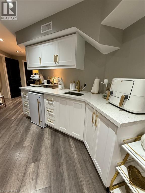Kitchen featuring white cabinets, dark wood finished floors, recessed lighting, light stone countertops, and fridge - 11 Donatello Court, Hamilton, ON - Indoor Photo Showing Kitchen