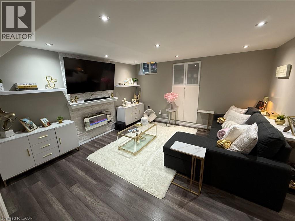 Living room featuring dark wood-type flooring, recessed lighting, and a stone fireplace - 11 Donatello Court, Hamilton, ON - Indoor Photo Showing Living Room