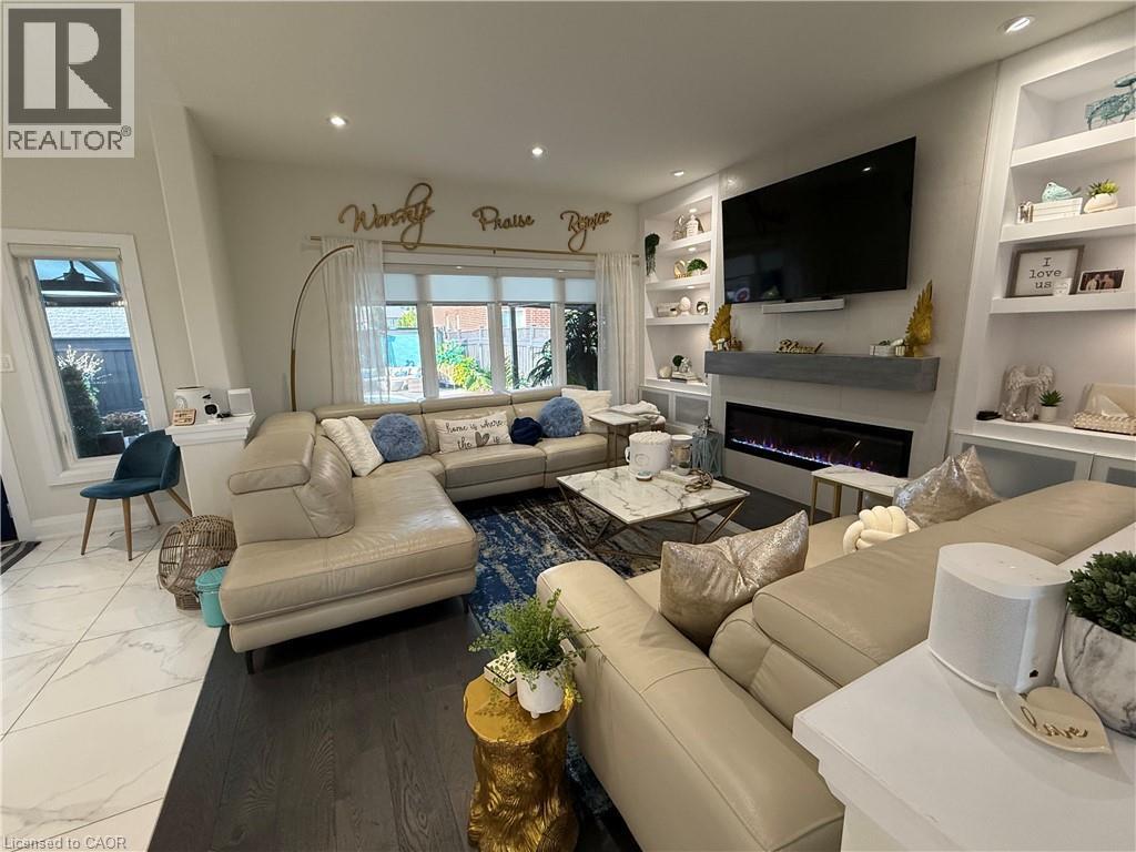 Living room featuring built in features, a glass covered fireplace, marble finish flooring, healthy amount of natural light, and recessed lighting - 11 Donatello Court, Hamilton, ON - Indoor Photo Showing Living Room With Fireplace