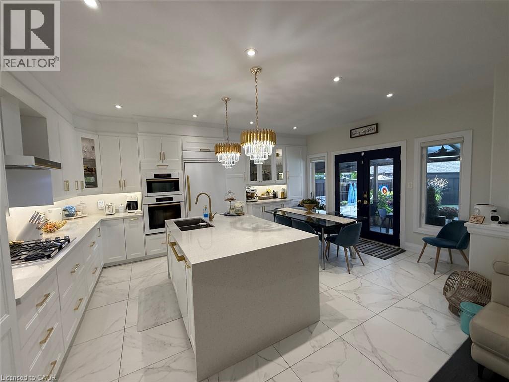 Kitchen featuring glass insert cabinets, decorative light fixtures, white cabinets, light stone counters, and french doors - 11 Donatello Court, Hamilton, ON - Indoor Photo Showing Kitchen With Upgraded Kitchen