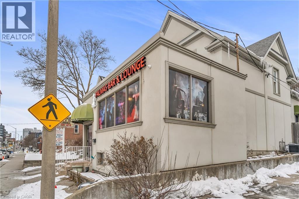 View of snow covered exterior featuring stucco siding and a cooling unit - 612 King Street E, Kitchener, ON
